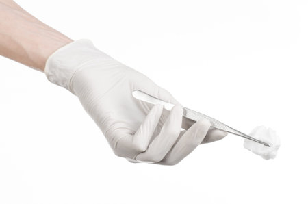 Medicine and Surgery theme: doctor's hand in a white glove holding tweezers with swab isolated on white background in studioの写真素材