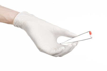 Pharmacology and Medical theme: doctor's hand in a white glove holding tweezers with red pill capsule isolated on white background in studioの写真素材