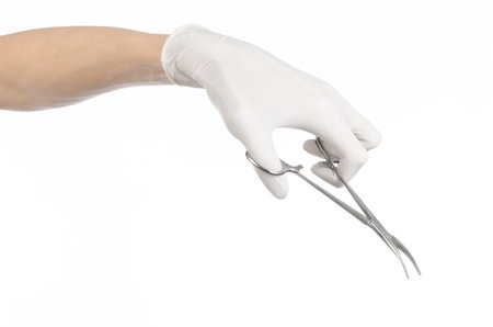 Surgery and Medical theme: doctor's hand in a white glove holding a surgical clip isolated on white...
