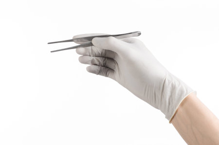 Medicine and Surgery theme: doctor's hand in a white glove holding tweezers isolated on white backgroundの写真素材