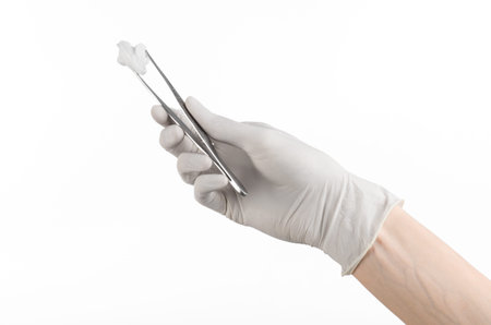 Medicine and Surgery theme: doctor's hand in a white glove holding tweezers with swab isolated on white background in studioの写真素材