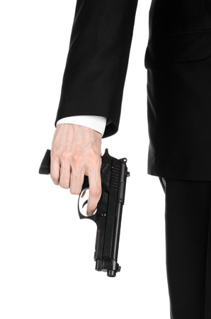 Firearms and security topic: a man in a black suit holding a gun on an isolated white backgroundの写真素材