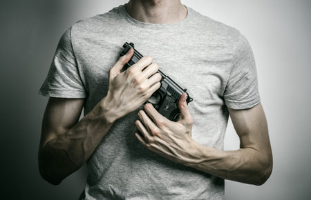 Horror and firearms topic: suicide with a gun on a gray background
