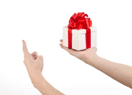 The theme of celebrations and gifts: hand holding a gift wrapped in white box with red ribbon and bow, the most beautiful gift isolated on white backgroundの写真素材