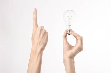 Energy consumption and energy saving topic: human hand holding a light bulb on a white backgroundの写真素材