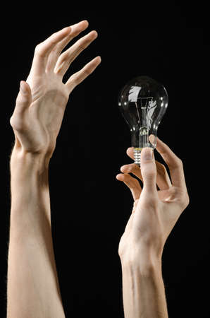Energy consumption and energy saving topic: human hand holding a light bulb on black backgroundの写真素材