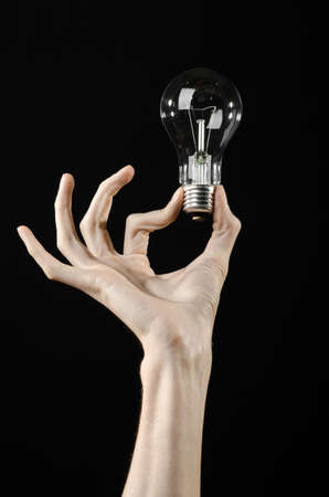 Energy consumption and energy saving topic: human hand holding a light bulb on black backgroundの写真素材