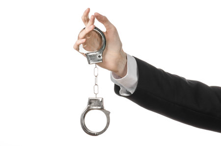 Corruption and bribery theme: businessman in a black suit with handcuffs on his hands on a white...