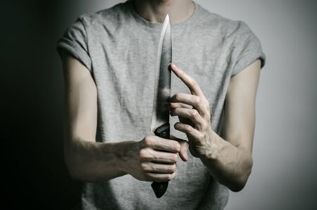 Murder and Halloween theme: a man holding a knife on a gray background studioの写真素材