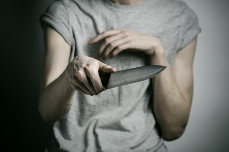 Murder and Halloween theme: a man holding a knife on a gray background studioの写真素材