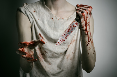 Blood and Halloween theme: man holding a bloody knife in his hand, a bloody murderer studioの写真素材