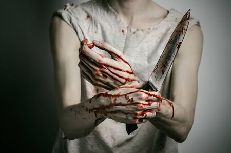 Blood and Halloween theme: man holding a bloody knife in his hand, a bloody murderer studioの写真素材