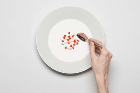 Medications and improper nutrition topic: human hand hold a plate with pills isolated on white background top view studioの写真素材