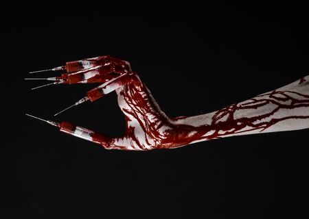 Bloody hand with syringe on the fingers, toes syringes, hand syringes, horrible bloody hand, halloween theme, zombie doctor, black background, isolatedの写真素材