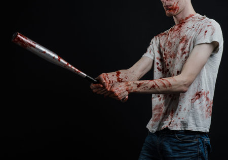 Bloody topic: The guy in a bloody T-shirt holding a bloody bat on a black background