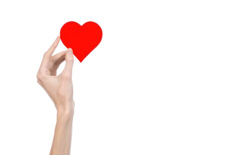 Valentine's Day and love theme: hand holding a red heart isolated on a white background in studioの写真素材