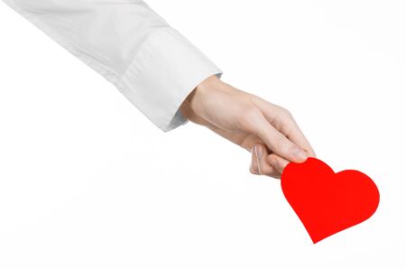 Heart Disease and Health Topic: hand doctor in a white shirt holding a card in the form of a red heart isolated on a white background in studioの写真素材