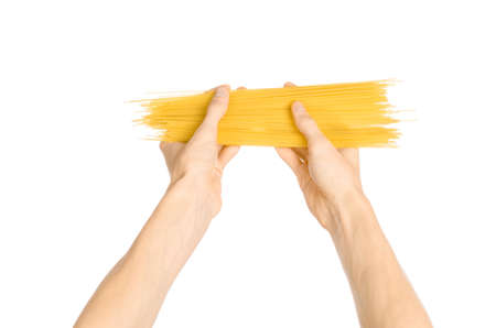 The kitchen and the cooking theme: man's hand holding a stack of raw spaghetti on an isolated white backgroundの写真素材
