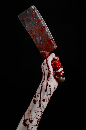 Bloody Halloween theme: bloody hand holding a large bloody kitchen knife on a black background isolatedの写真素材