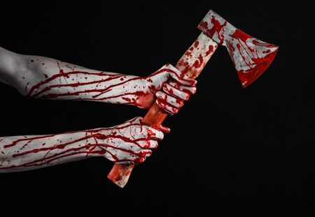 Bloody Halloween theme: bloody hand holding a bloody butcher's ax isolated on black background in studioの写真素材