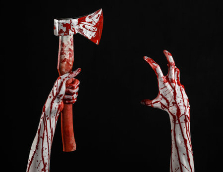 Bloody Halloween theme: bloody hand holding a bloody butcher's ax isolated on black background in...