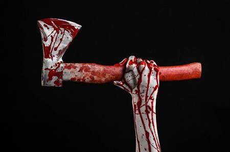 Bloody Halloween theme: bloody hand holding a bloody butcher's ax isolated on black background in studioの写真素材