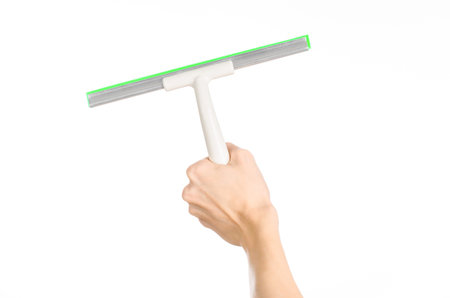 Household cleaning and washing windows theme: man's hand holding a green scraper windows isolated on...