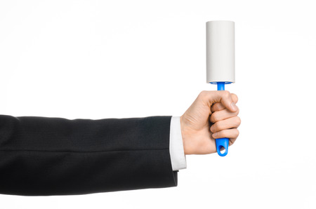 Dry cleaning and business theme: a man in a black suit holding a blue sticky brush for cleaning clothes and furniture from dust isolated on white backgroundの写真素材