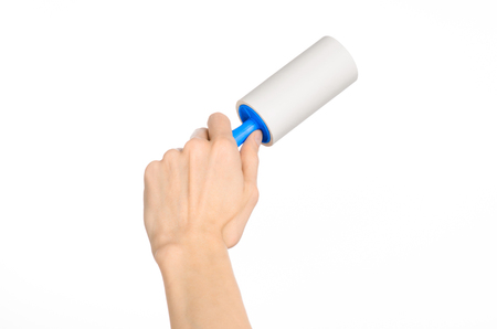 Clean clothes and cleaning the house topic: human hand holding a blue sticky brush for cleaning clothes and furniture from dust isolated on white backgroundの写真素材