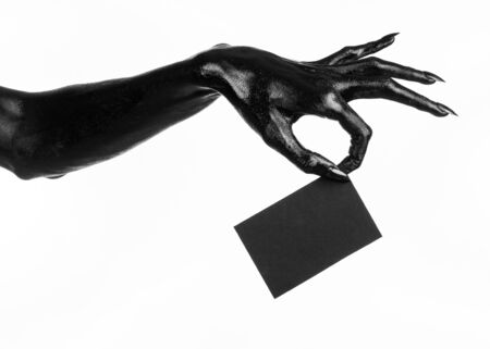 Halloween and gothic theme: The Black Hand of death holding a blank black card on white isolated background in the studio, the walking deadの写真素材