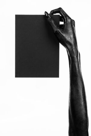 Halloween and gothic theme: The Black Hand of death holding a blank black card on white isolated background in the studio, the walking deadの写真素材