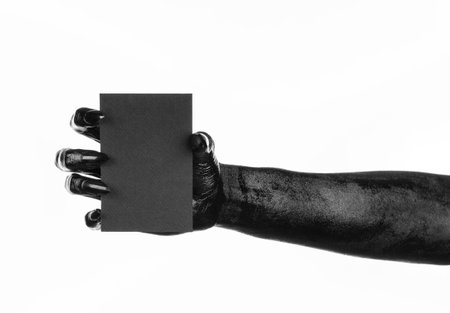 Halloween and gothic theme: The Black Hand of death holding a blank black card on white isolated background in the studio, the walking deadの写真素材