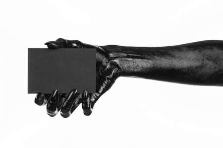 Halloween and gothic theme: The Black Hand of death holding a blank black card on white isolated background in the studio, the walking deadの写真素材