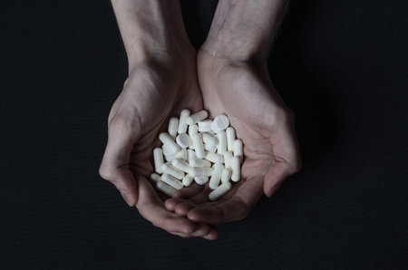 Addiction topic: the addict keeps tablet with a drug on a dark background studio