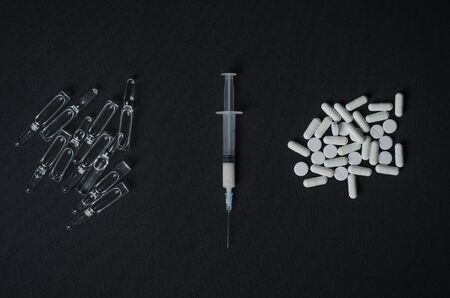 Addiction topic: ampoule with drug and syringe tablets lie on a dark background studioの写真素材