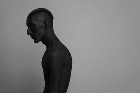 Gothic and Halloween theme: a man with black skin is isolated on a gray background in the studio, the Black Death body art studioの写真素材