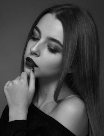 Dramatic black and white portrait of a beautiful girl on a dark background in the studioの写真素材