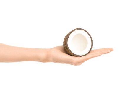 Healthy eating and diet Topic: Human hand holding a half of coconut isolated on a white background in the studio shotの写真素材