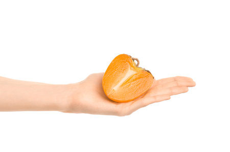 Healthy eating and diet Topic: Human hand holding a half of persimmons isolated on white background in the studio shotの写真素材