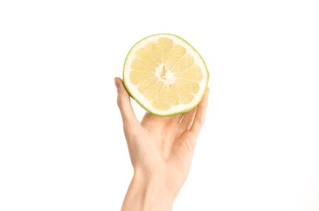 Healthy eating and diet Topic: Human hand holding a half sweetie isolated on white background in the studio, first-person view shotの写真素材
