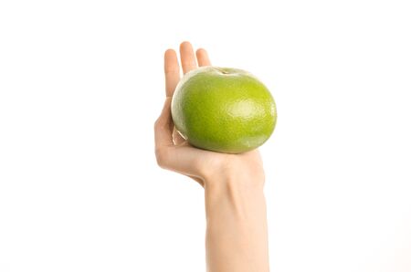 Healthy eating and diet Topic: Human hand holding a green sweetie isolated on a white background in the studio, first-person view shotの写真素材