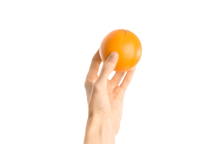 Healthy eating and diet Topic: Human hand holds a ripe orange isolated on a white background in the studio, first-person view shotの写真素材