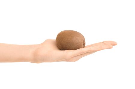 Healthy eating and diet Topic: Human hand holding a ripe kiwi fruit isolated on a white background in the studio shotの写真素材