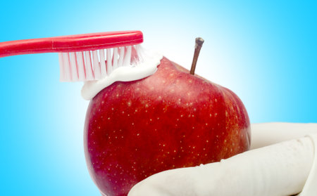 Tooth brushing tecnique with toothpaste  and red apple isolated in white backgroundの写真素材