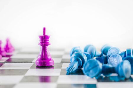 Purple king knocked down blue team in a chessboard top view isolated in white backgroundの写真素材