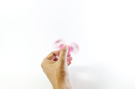 Pink colour fidget spinner holding and moving by a hand isolated in whiteの写真素材