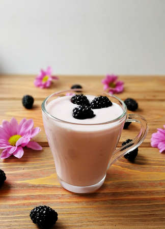 BlackBerry with yogurt on aged wooden background with flowersの写真素材