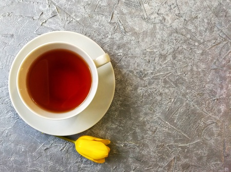 yellow Tulip with a Cup of tea on a grey textured backgroundの写真素材