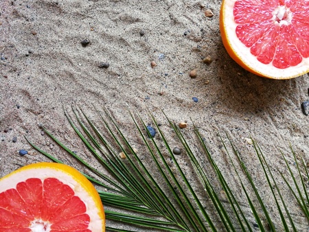 pineapple , grapefruit and bananas with a green branch of palm trees on the sand with the phoneの写真素材