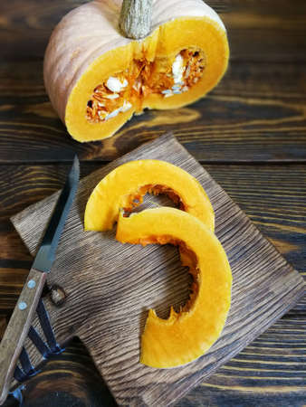 sliced pumpkin with a knife on a wooden Board and the old backgroundの写真素材